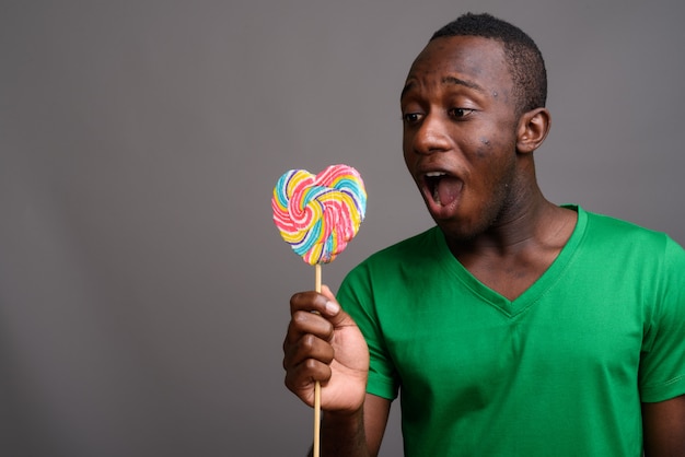 Joven africana con camisa verde en la pared gris