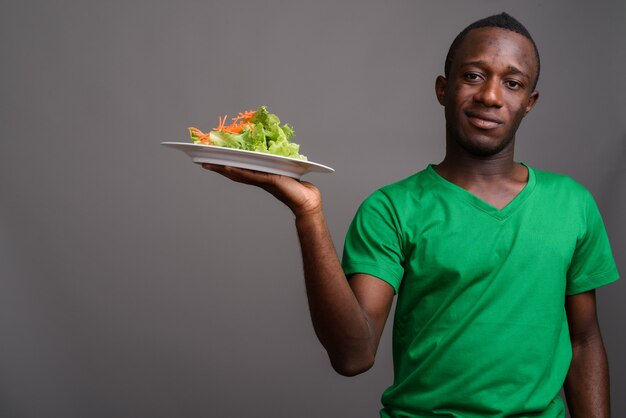 Joven africana con camisa verde en la pared gris