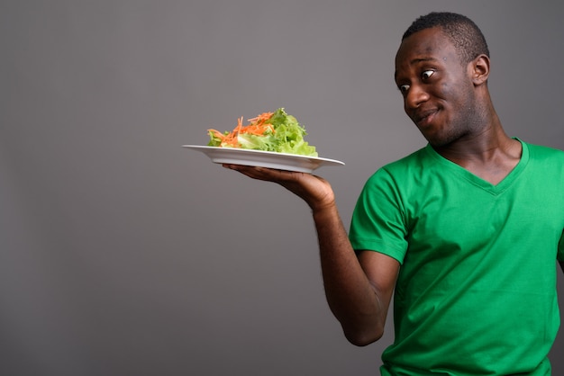 Joven africana con camisa verde en la pared gris