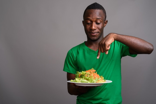 Joven africana con camisa verde en la pared gris