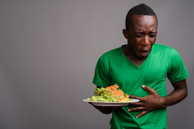 Joven africana con camisa verde en la pared gris