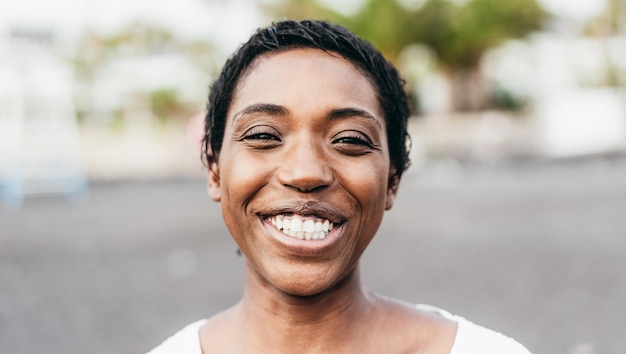 Joven africana sonriendo a la cámara al aire libre - Centrarse en la cara