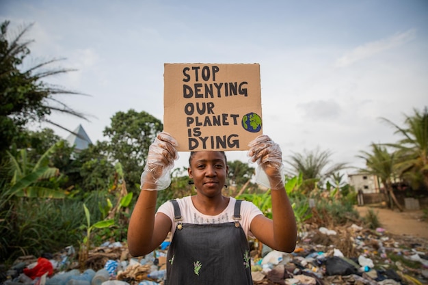 Joven africana sosteniendo un cartel que deja de negar que nuestro planeta está muriendo Concepto de contaminación