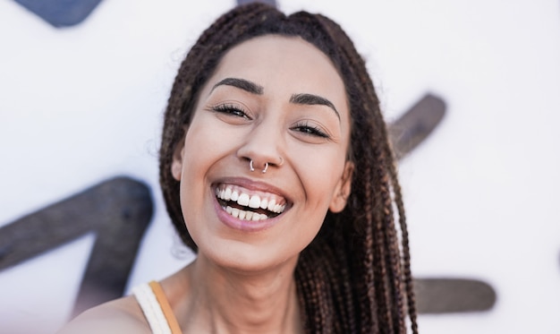 Foto joven africana tomando un selfie en la ciudad mediante teléfono móvil - niña de raza mixta sonriendo a la cámara