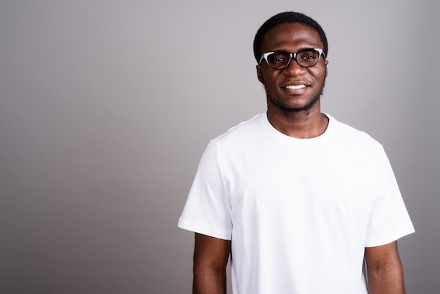 Joven africano con camisa blanca y anteojos en gris