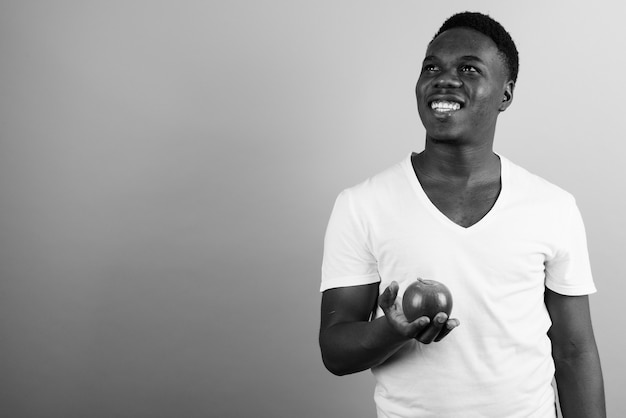 joven africano con camisa blanca contra la pared blanca. en blanco y negro