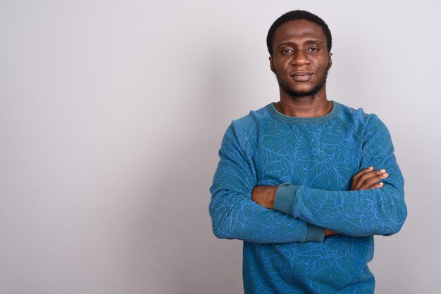 Joven africano con camisa de manga larga azul sobre gris