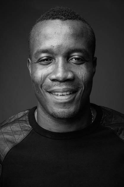 Foto joven africano con camisa negra de manga larga contra la pared gris. en blanco y negro