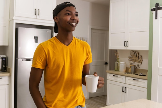 Joven africano en la cocina bebiendo una taza de café