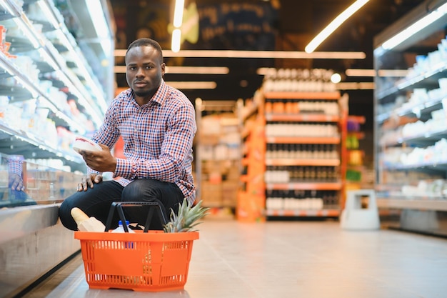 Joven africano comprando en la sección de comestibles en el supermercado