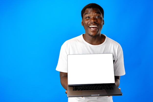Joven africano con una computadora portátil contra un fondo azul