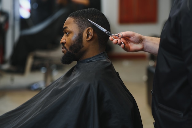 Joven africano consiguiendo nuevo corte de pelo en peluquería