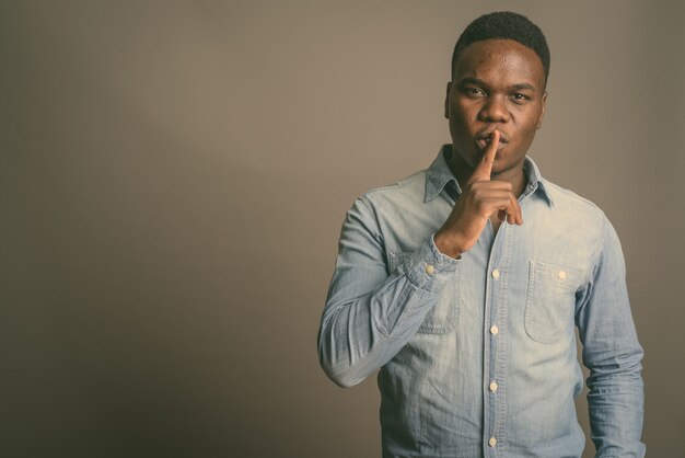 Joven africano con el dedo en los labios en blanco y negro