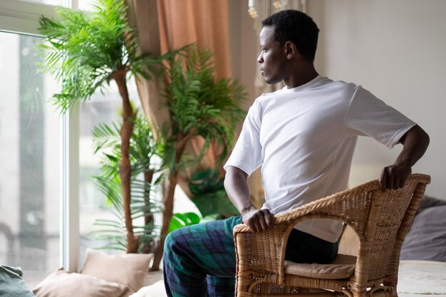 Joven africano deportivo practicando yoga usando una silla haciendo una pose de silla giratoria parivrtta utkatasana