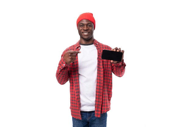 Un joven africano étnico en una imagen elegante muestra una maqueta de teléfono inteligente con la mano aislada en un