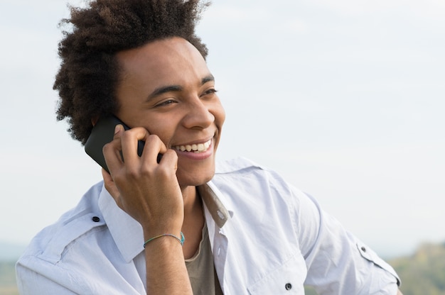 Joven africano feliz hablando por teléfono móvil