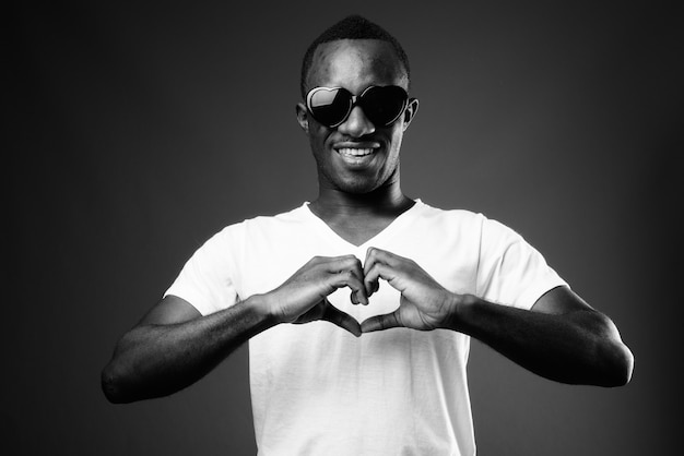 Joven africano con gafas de sol mientras hace el signo del corazón