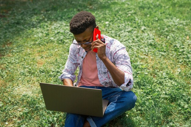 joven, africano, macho, con, teléfono móvil, y, computador portatil