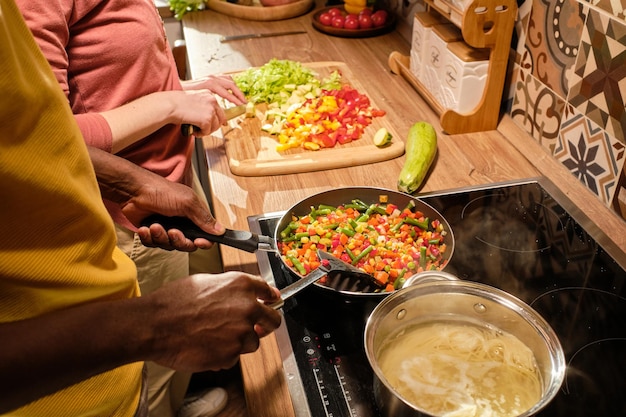 Foto joven africano mezclando verduras picadas en una sartén