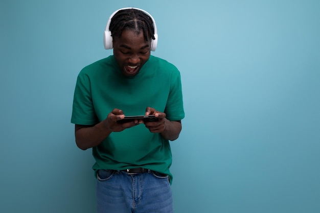 Joven africano viendo video con auriculares inalámbricos y teléfono móvil