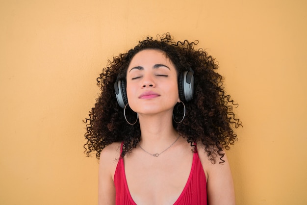 Joven afro escuchando música con auriculares