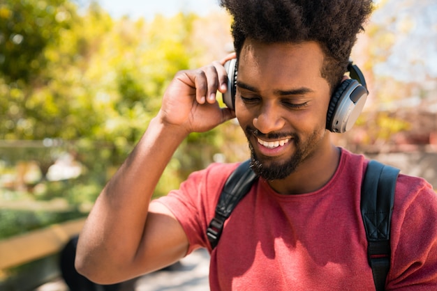 Joven afro escuchando música con auriculares.