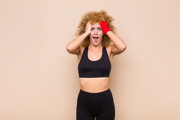 Joven afro levantando las manos a la cabeza, con la boca abierta, sintiéndose extremadamente afortunado, sorprendido, emocionado y feliz concepto deportivo