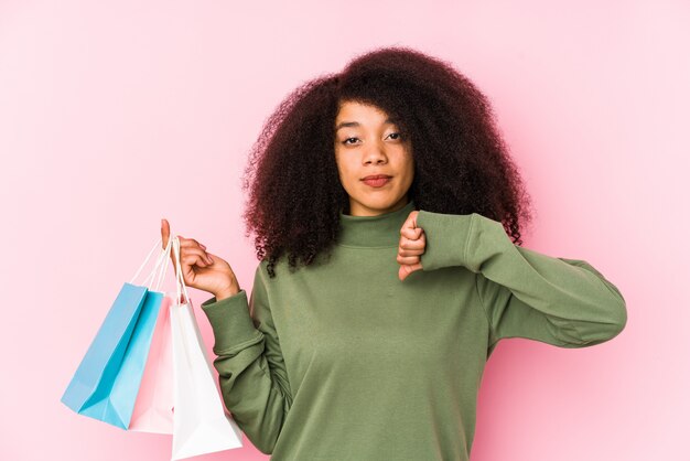 Joven afro mujer aislada de compras Joven afro mujer comprando isolaYoung joven mujer sosteniendo una rosas aisladas mostrando un gesto de disgusto, pulgares abajo.