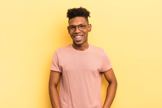 Joven afro negro con una gran sonrisa amistosa y despreocupada que se ve positiva, relajada y feliz escalofriante