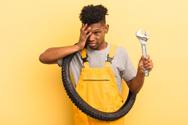 Joven afro negro que se siente aburrido, frustrado y somnoliento después de un aburrido concepto mecánico de bicicletas