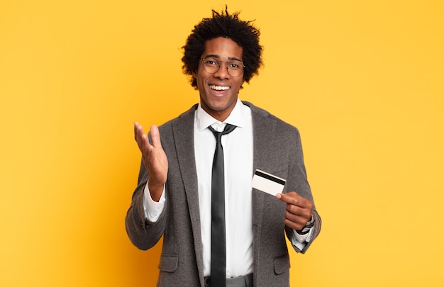 Joven afro negro que se siente feliz, sorprendido y alegre, sonriendo con actitud positiva, dándose cuenta de una solución o idea