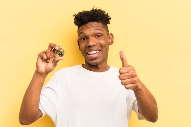 Joven afro negro que se siente orgulloso sonriendo positivamente con los pulgares hacia arriba concepto bitcoin