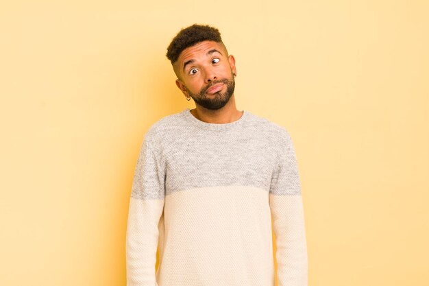 Joven afro que parece tonto y divertido con una tonta expresión bizca bromeando y bromeando