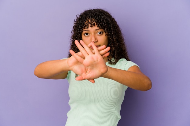 Joven afroamericana afro aislado haciendo un gesto de negación