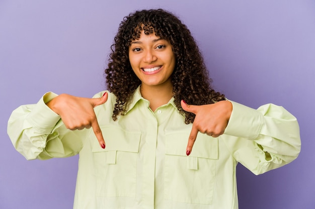 Foto joven afroamericana afro apunta hacia abajo con los dedos, sentimiento positivo.