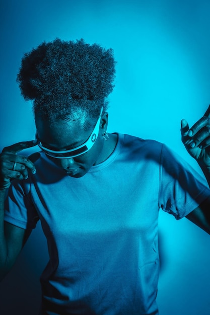 Joven afroamericana aislada en un fondo azul con gafas futuristas estudio disparar futuro concepto