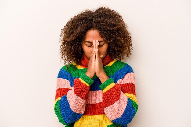 Joven afroamericana aislada de fondo blanco rezando mostrando devoción persona religiosa en busca de inspiración divina