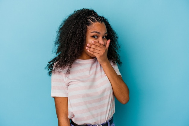 Joven afroamericana aislada en la pared azul asustada y asustada