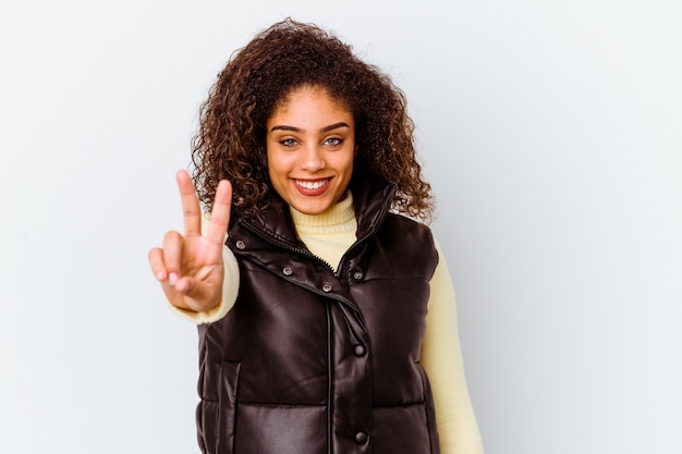 Joven afroamericana aislada en la pared blanca que muestra el signo de la victoria y una amplia sonrisa.