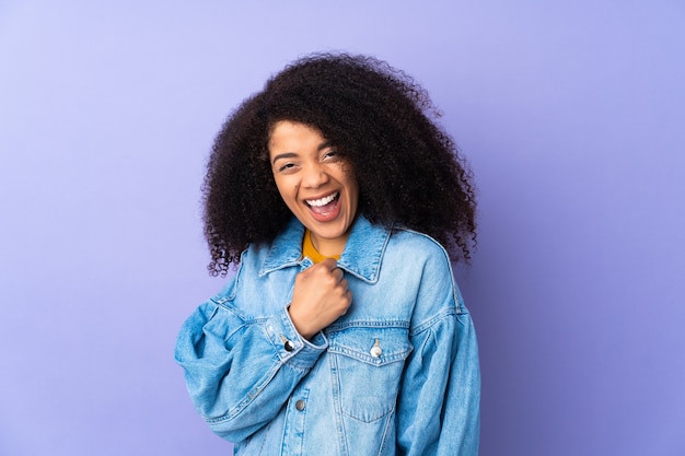 Joven afroamericana aislada en púrpura celebrando una victoria