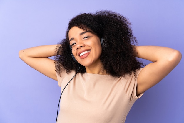 Joven afroamericana aislada en púrpura escuchando música