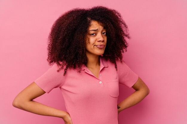 Joven afroamericana aislada en rosa confundida, se siente dudosa e insegura.