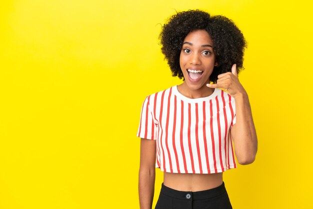 Joven afroamericana aislada sobre fondo amarillo haciendo gesto de teléfono. Llámame señal