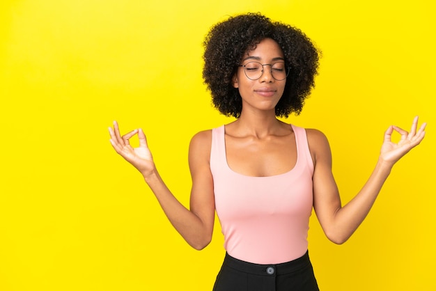 Joven afroamericana aislada sobre fondo amarillo en pose zen