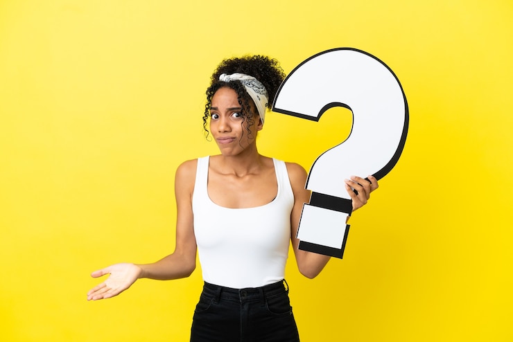 Foto joven afroamericana aislada sobre fondo amarillo sosteniendo un icono de signo de interrogación y tener dudas
