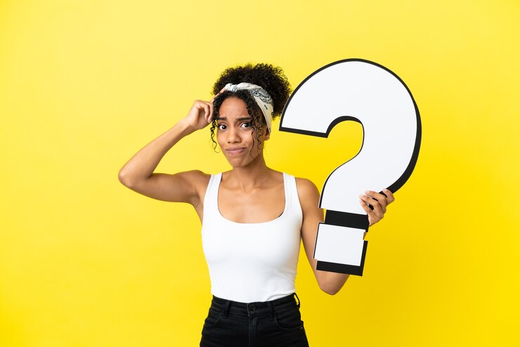 Foto joven afroamericana aislada sobre fondo amarillo sosteniendo un icono de signo de interrogación y tener dudas