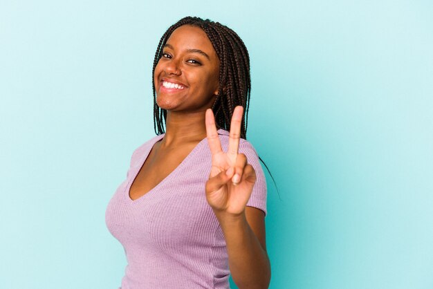 Joven afroamericana aislada sobre fondo azul alegre y despreocupado mostrando un símbolo de paz con los dedos.