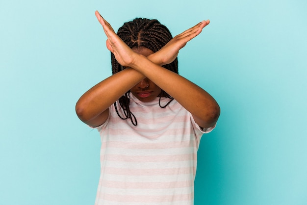 Joven afroamericana aislada sobre fondo azul manteniendo los dos brazos cruzados, concepto de negación.
