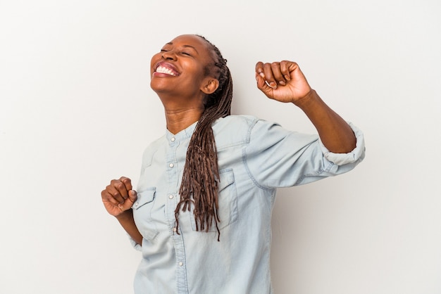 Joven afroamericana aislada sobre fondo blanco celebrando un día especial, salta y levanta los brazos con energía.