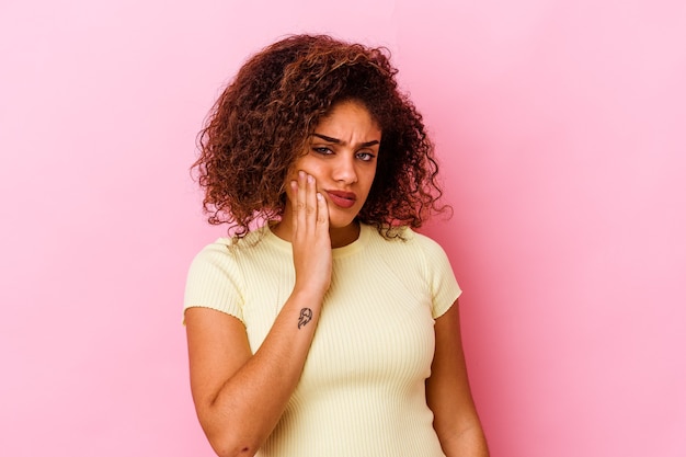 Joven afroamericana aislada sobre fondo rosa con un fuerte dolor de dientes, dolor de muelas.